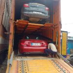 Yellow container carrying a red and grey car, prepared for car carrier service in Bangalore.