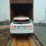 A white car is loading in a container and going for transport by a 4 wheeler movers vehicle transport company in Bangalore. 